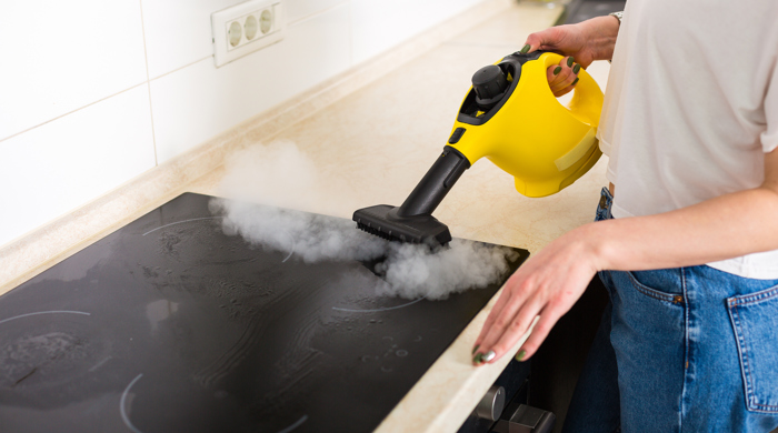 A steam cleaner being used on an induction hob