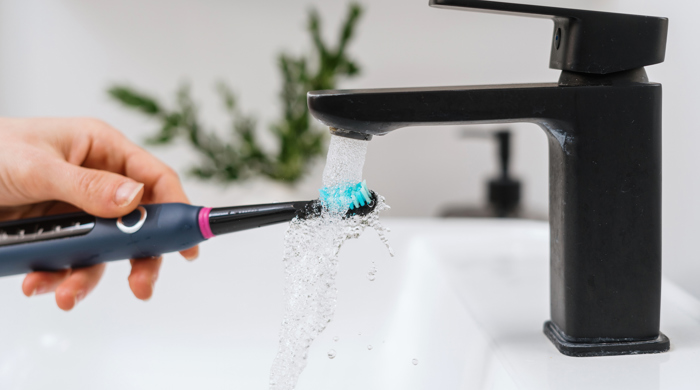 A woman cleaning her electric toothbrush